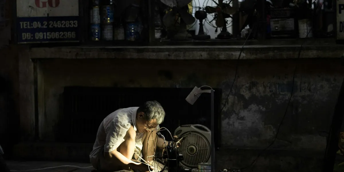 man in gray dress shirt beside black desk fan